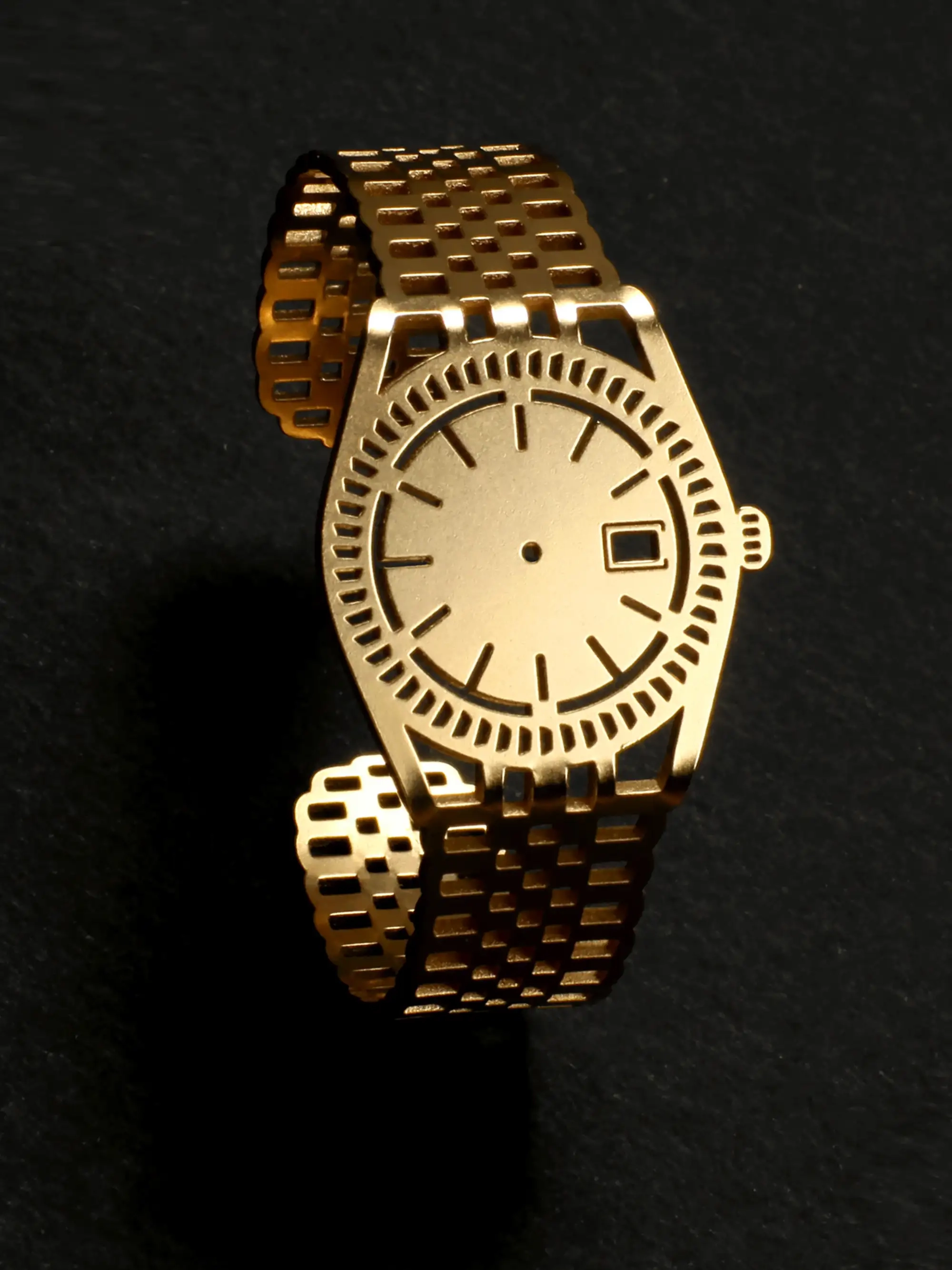 Gold plated minimalist bracelet that looks like a watch, but without showing the time, on black background, golden shining