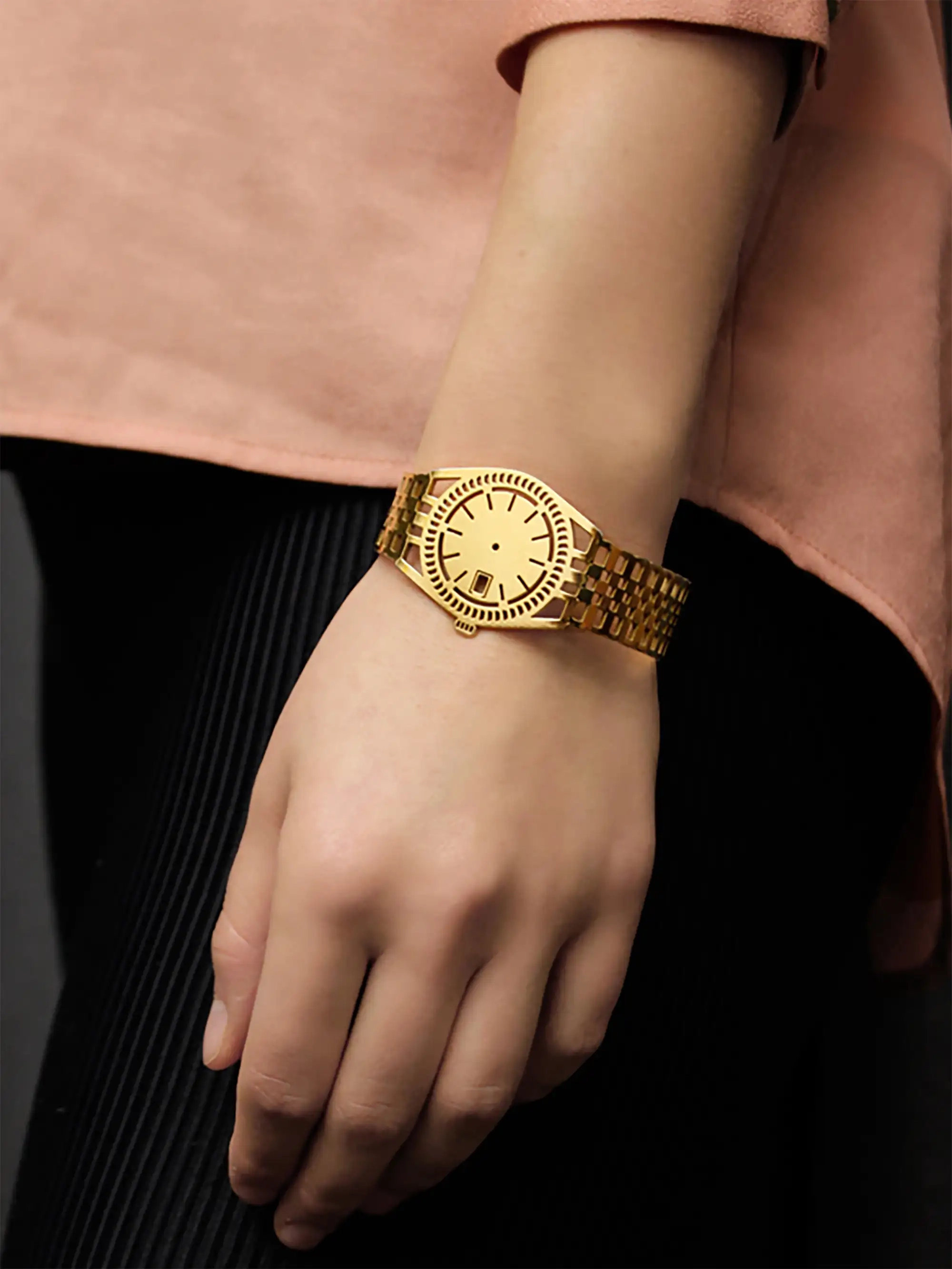 Minimalist golden TIMEPEACE bracelet worn on wrist, modern timepiece jewelry symbolizing freedom from time and enjoy life, worn with black skirt and pink shirt