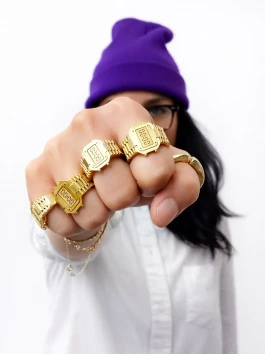 Young woman extending her fist forward, wearing multiple TIMEPEACE watch rings on every finger, recycled sterling silver jewelry inspired by digital watches 