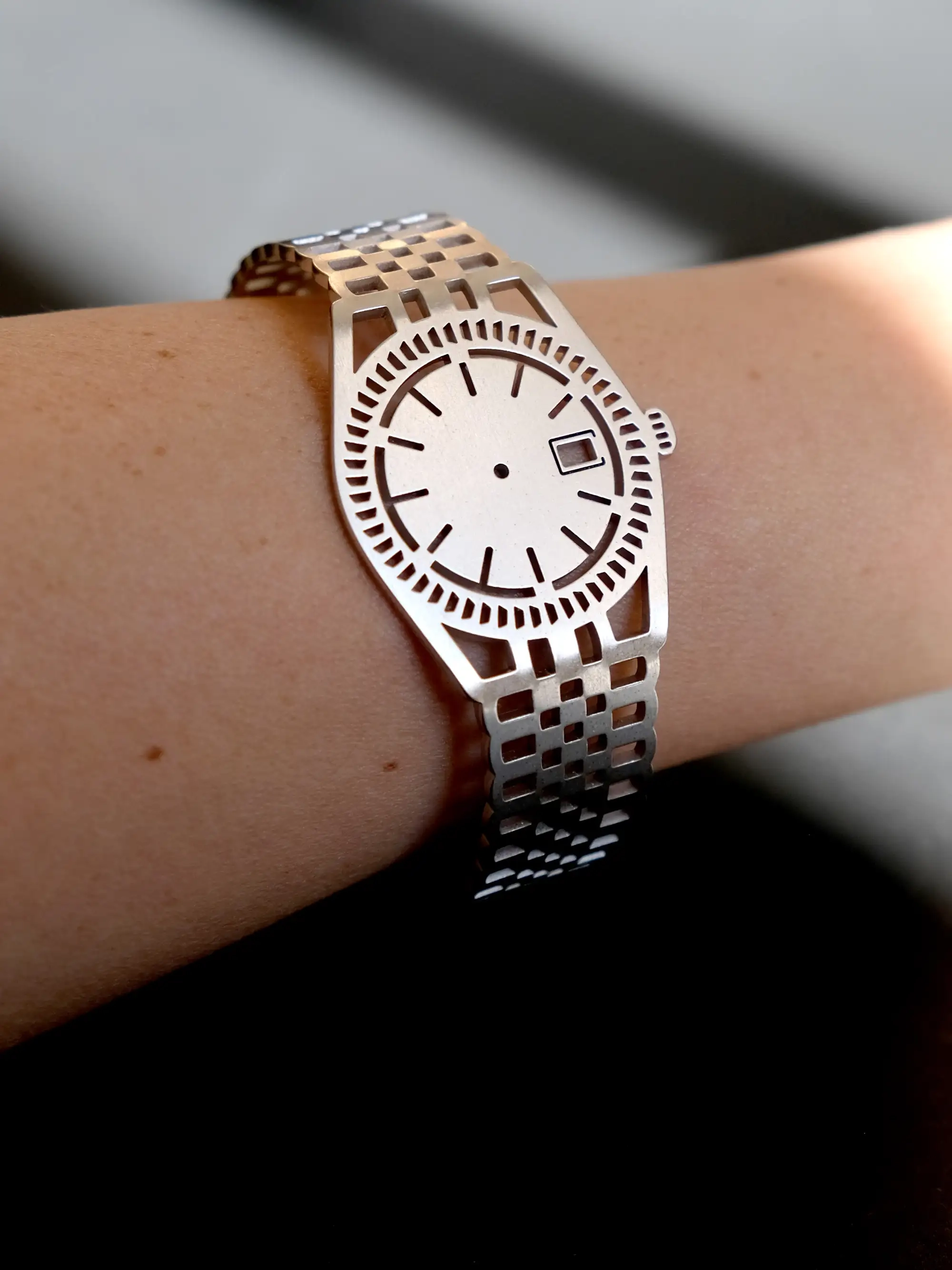 Silver TIMEPEACE bracelet worn on the wrist, minimalist watch-style jewelry with polished metal finish against a black background