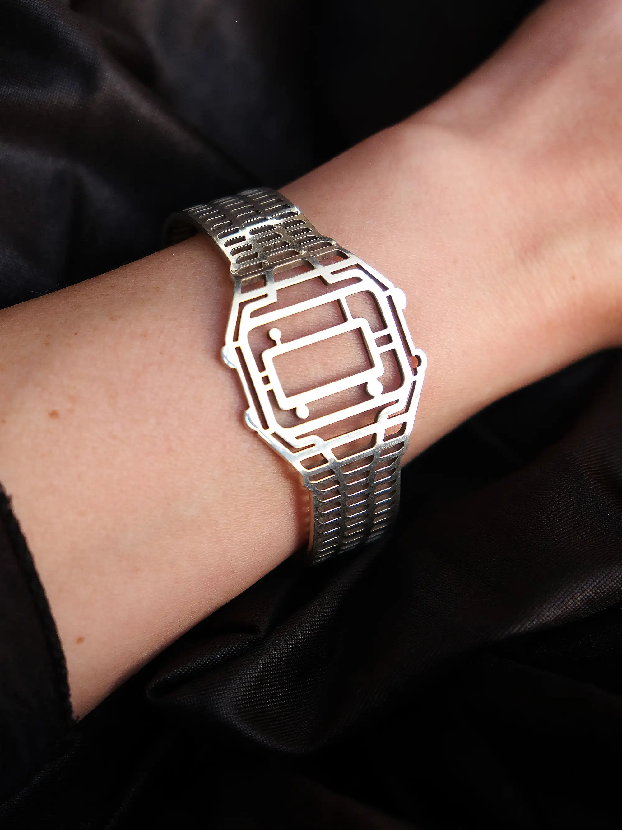 Minimalist golden TIMEPEACE bracelet worn on the wrist, modern watch-inspired timepiece jewelry styled with a black leather