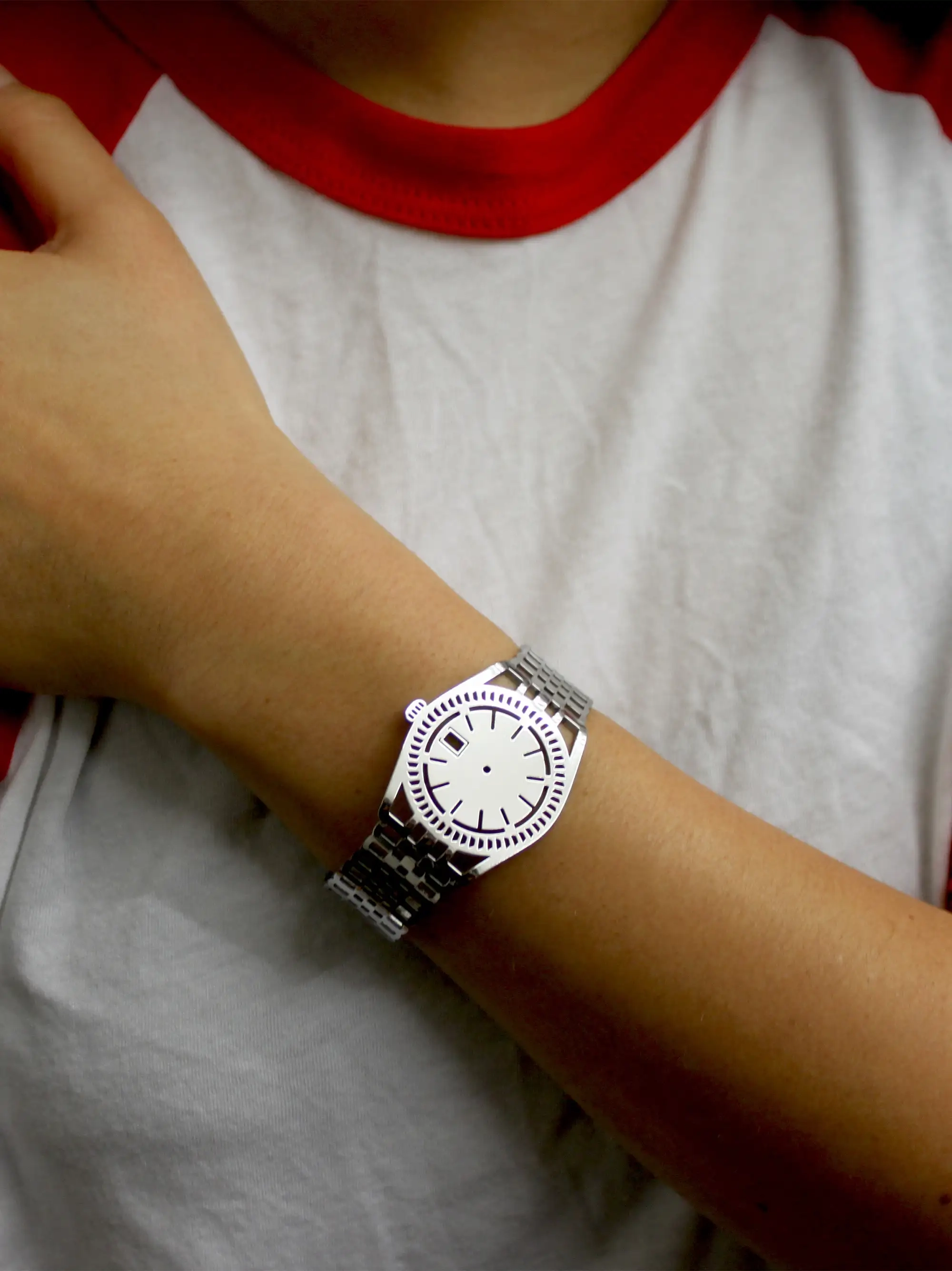 Silver TIMEPEACE bracelet worn on the wrist, minimalist watch-style jewelry with polished silver finish worn with a white red t-shirt