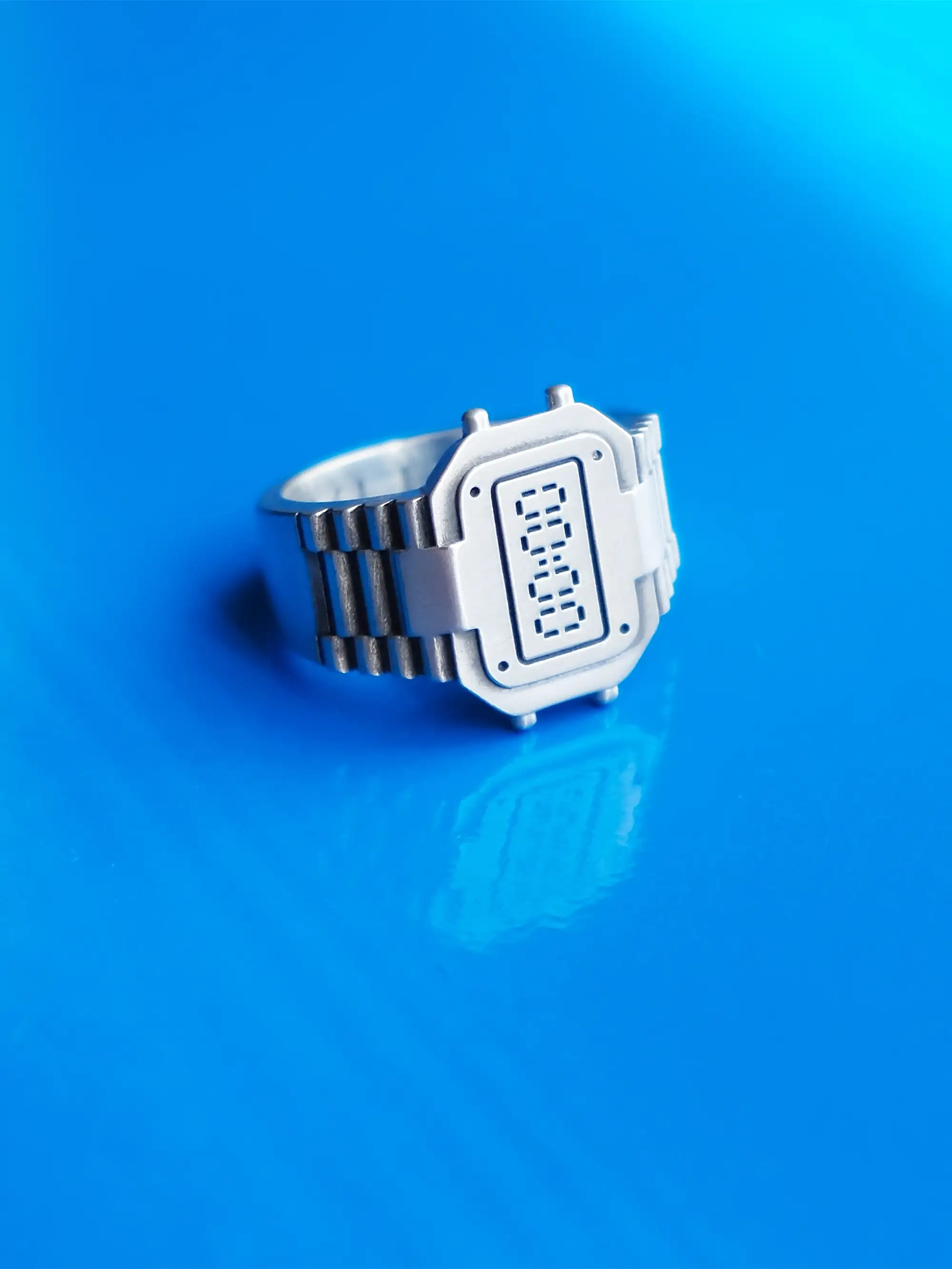 TIMEPEACE clockring made from recycled 925 sterling silver, watch-inspired ring without time display symbolizing forgive and forget, on shiny blue background